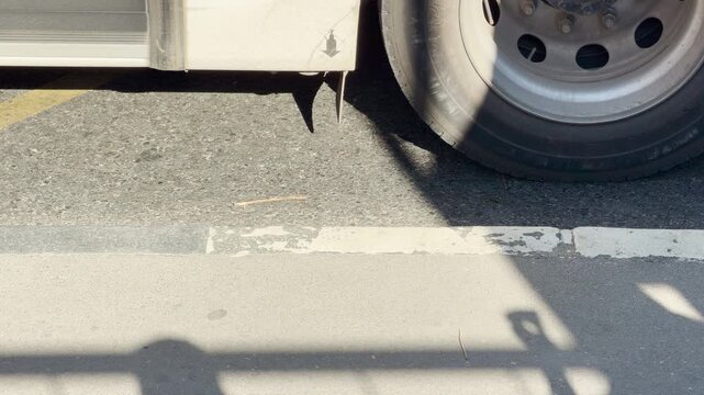 An arriving bus wheel stops by the sunny curb at a transit station in Simferopol, Crimea. This brings a warm feeling of relief and calm anticipation for the journey ahead.