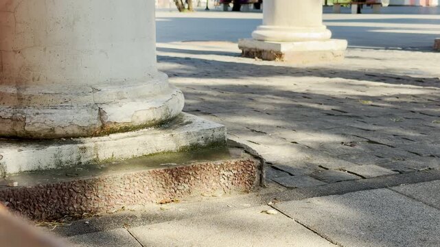 Old stone columns stand tall in a sunny public square in Simferopol, Crimea. The historic scene evokes a powerful sense of peaceful nostalgia and calm strength.