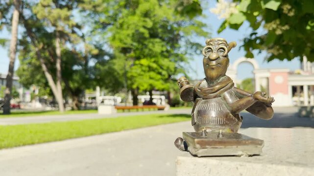 A whimsical bronze bee figurine smiles cheerfully on a stone ledge in a sunny park in Simferopol, Crimea. This cute character brings a joyful and happy feeling to the bright outdoor day.