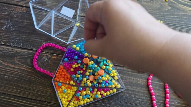 Brightly colored sets of beads, seed beads, and decorative elements in plastic organizers for arts and crafts. Supplies for making jewelry, bracelets, crafts, and educational activities for children.