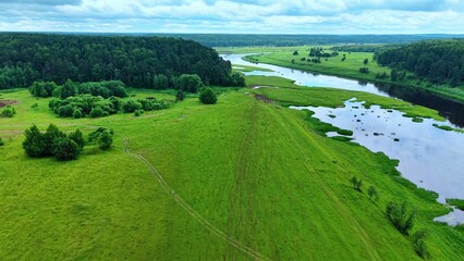 Obraz premium Aerial view of lush green landscape showing winding river and dense forest in summer