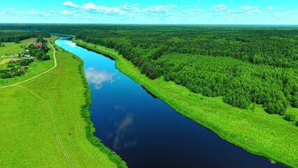 Obraz premium Winding river surrounded by lush green forests and farmland under a clear blue sky