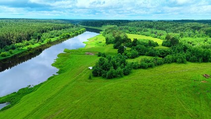 Obraz premium Aerial view of the lush green riverbank landscape with dense forest and flowing river