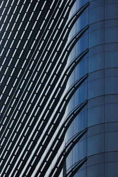 A modern skyscraper facade featuring sleek glass panels and structured steel louvers. 