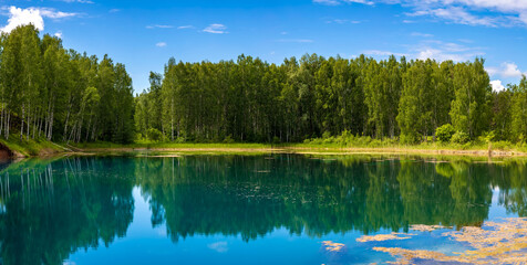 Fototapeta premium Panorama of a forest lake with clouds on a summer day.