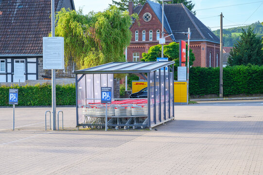Iserlohn, Germany - June 18, 2026: Penny supermarket parking lot with shopping cart shelter, DHL Packstation, and historic German buildings