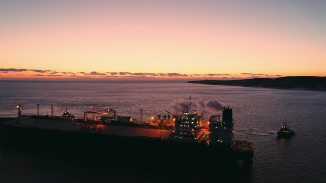A large LNG tanker docks at an industrial port terminal for cargo operations at dusk