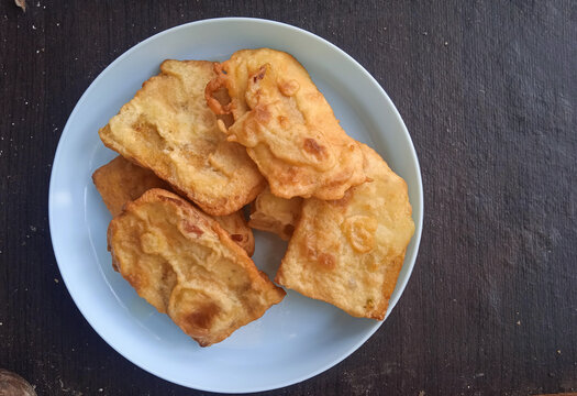 battered and fried tempe served on a blue plastic plate on a dark wooden table.