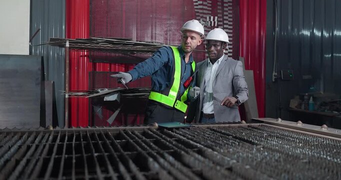 Sales engineer briefs a client in a metal workshop, using sample parts and technical references to present fabrication capabilities, customization options and production solutions.
