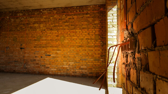 Unfinished brick building interior with exposed electrical wiring and conduits