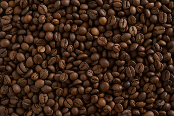 Fototapeta premium Roasted coffee beans background. Full frame close-up texture of dark brown aromatic coffee beans, ideal for wallpaper, banner, or food and drink backdrop.