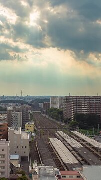 Vertical time lapse of crepuscular rays over a railway station and tracks at dusk