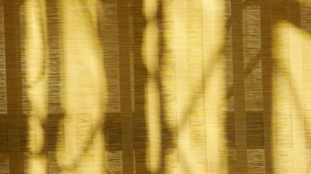 Elegant shadows fall over textured bamboo blinds in a sunlit room. This close-up creates a warm, dreamlike feeling of quiet comfort. The natural fibers glow with a serene and peaceful energy.