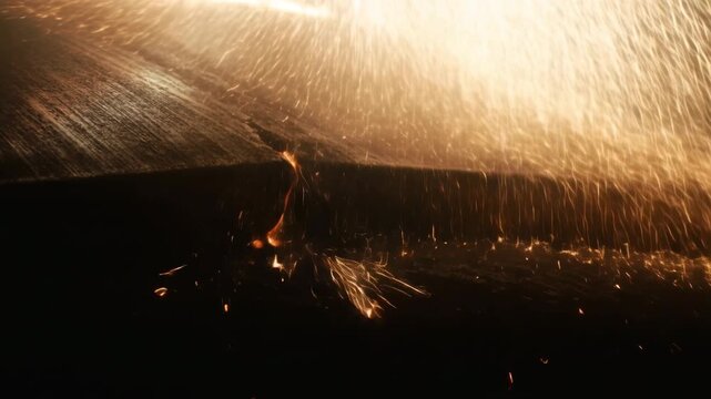 Golden sparks and molten droplets pouring over dark textured metal edge with intense warm backlight, high contrast industrial atmosphere, glowing trails, heat, impact, dramatic shadows