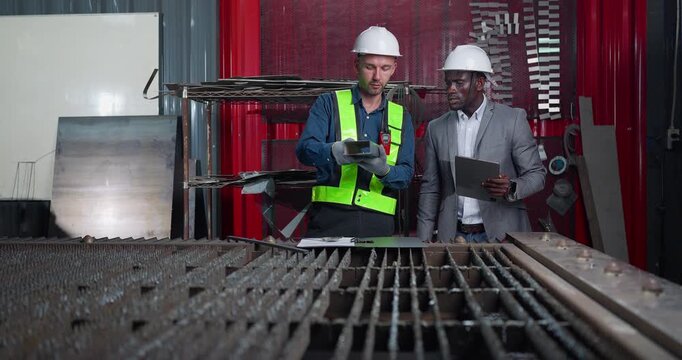 Sales engineer briefs a client in a metal workshop, using sample parts and technical references to present fabrication capabilities, customization options and production solutions.
