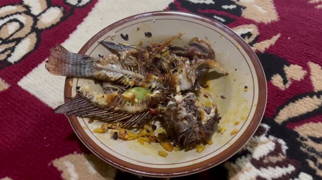 Leftover fried fish bone on a plate after a delicious meal