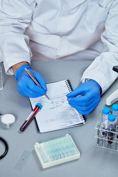 Blood sample collection tubes in laboratory rack beside microscope
