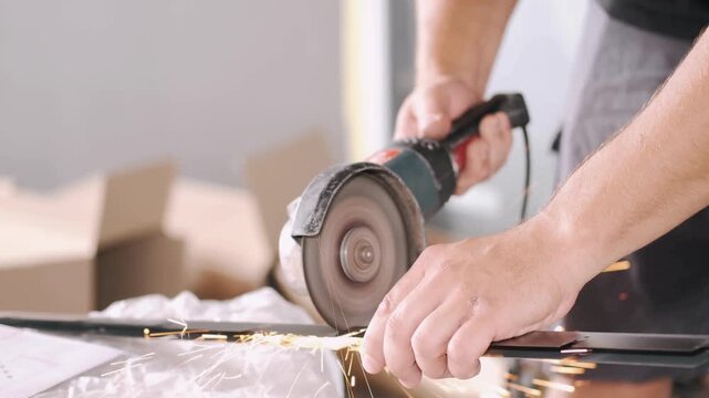 Man using angle grinder to cut metal with sparks flying everywhere in workshop
