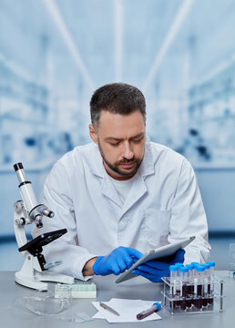 Medical laboratory scientist using digital tablet for clinical data analysis, healthcare researcher reviewing laboratory results and diagnostic information