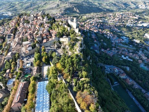 Aerial view of Guaita Tower on the rocky cliffs of Mount Titano, overlooking the historic old town with stone buildings and terracotta rooftops in Citta di San Marino, San Marino, San Marino.