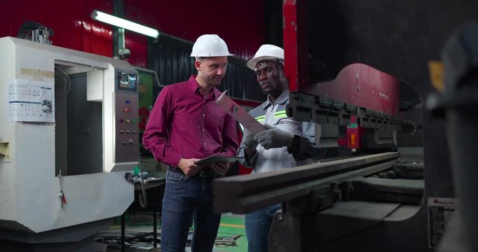 Sales engineer briefs a client in a metal workshop, using sample parts and technical references to present fabrication capabilities, customization options and production solutions.
