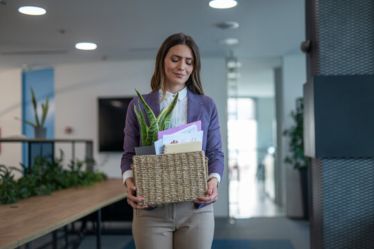 Woman carrying a box of personal items leaving the office after being laid off