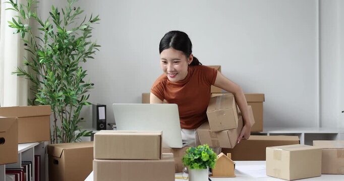 Asian woman packing delivery boxes for shipping, managing online business from home, processing e-commerce orders, working on small business logistics