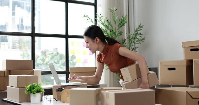 Asian woman packing delivery boxes for shipping, managing online business from home, processing e-commerce orders, working on small business logistics
