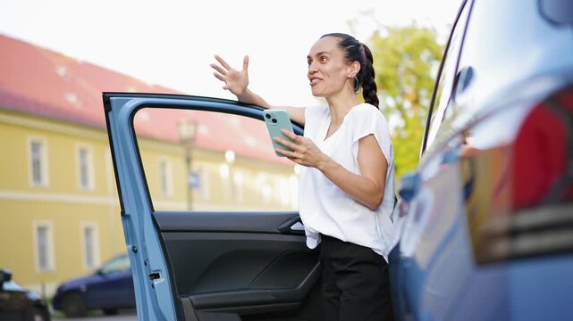 Expressive young Hispanic woman sharing exciting news during a video call while standing next to a car, capturing emotions, connection and modern communication.