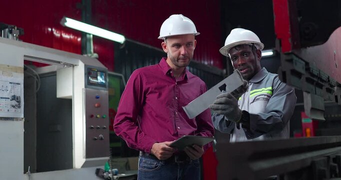 Sales engineer briefs a client in a metal workshop, using sample parts and technical references to present fabrication capabilities, customization options and production solutions.
