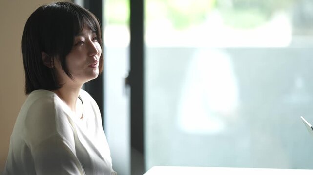 Soft light illuminates a quiet moment. She smiles gently, eyes closed. Warm, calm, intimate atmosphere. Perfect for serene cafe or study scenes. Natural, understated emotion
