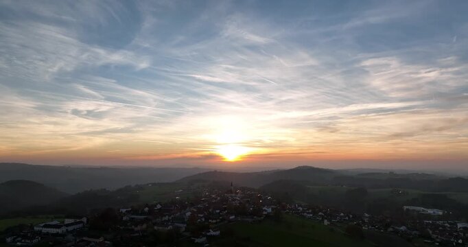 Stimmungsvoller Sonnenuntergang &uuml;ber einer h&uuml;geligen Landschaft mit weitem Ausblick in Niederbayern, warmem Licht, Wolkenhimmel und ruhiger Naturatmosph&auml;re.
