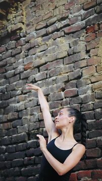 Waist-up portrait of a young beautiful Hispanic woman slowly dancing in front of a brick wall, capturing elegance, movement and urban fashion mood.