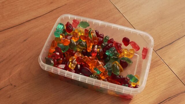 Marmalade sweets of different shapes and colors in a plastic box.