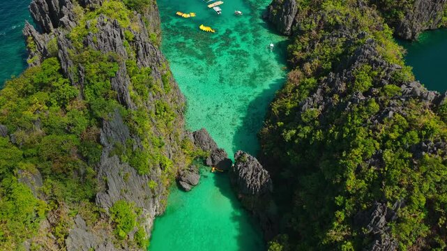 Aerial Forward Descent Over Small Lagoon in El Nido, Philippines. Cinematic Drone Push In and Pedestal Down View of Clear Turquoise Water and Limestone Karst Cliffs.