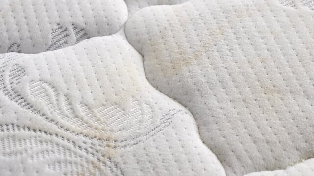Dirty mattress surface showing multiple yellow stains