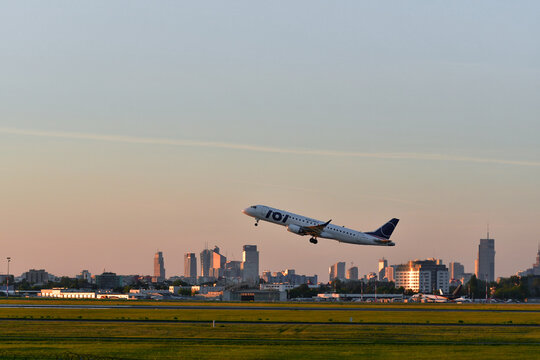 Boeing 737 taking off from Warsaw Chopin Airport with Warsaw skyline at sunset