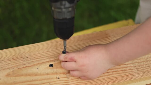 Screwdriver. Teenager. Screw. Board. Using a screwdriver. Slow motion video. High quality 4k footage