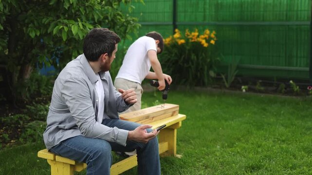 A man uses a smartphone. A teenager makes things with his hands. A screwdriver. Slow motion video. High quality 4k footage