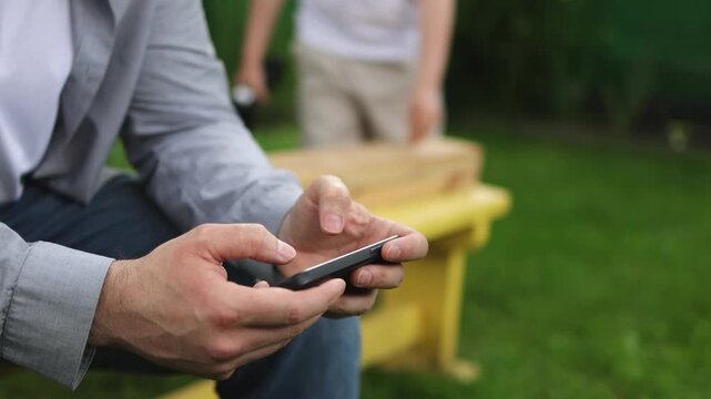 A man uses a smartphone. A teenager makes things with his hands. A screwdriver. Slow motion video. High quality 4k footage
