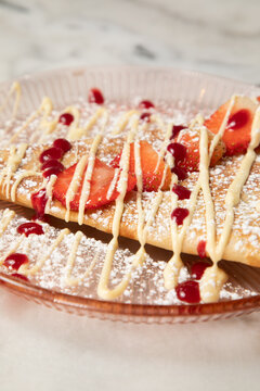 D&eacute;gustation de cr&ecirc;pes aux fraises avec sauce sur une assiette