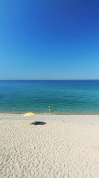 Aerial View of Woman with Yellow Umbrella Swimming in Aegean Sea Greece