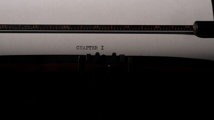 Typewriter carriage holding a sheet of white paper with the words chapter i typed in the center. Symbolizing the beginning of a fresh story. A new book © Aliaksandr