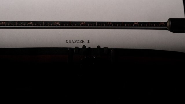 Typewriter carriage holding a sheet of white paper with the words chapter i typed in the center. Symbolizing the beginning of a fresh story. A new book