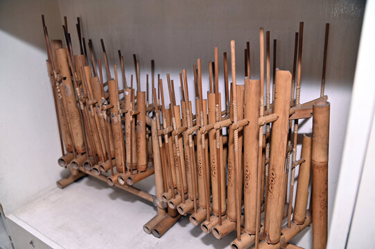 multiple sets of bamboo angklung instruments arranged on a white shelf