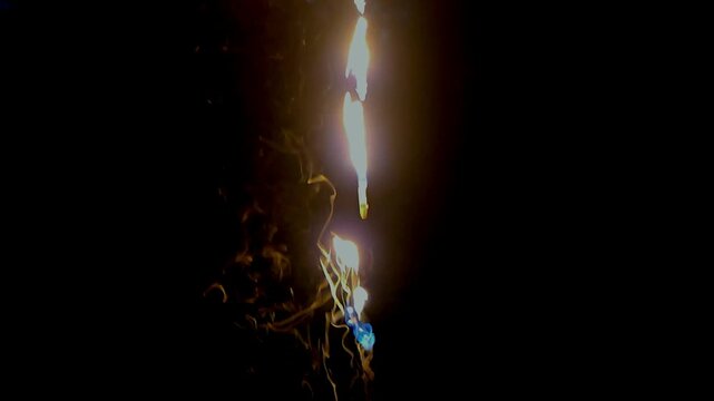 Abstract close-up footage of blue flames and swirling smoke rising from burning plastic against a deep black background. The flowing smoke creates dramatic organic patterns