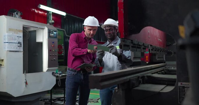 Sales engineer briefs a client in a metal workshop, using sample parts and technical references to present fabrication capabilities, customization options and production solutions.
