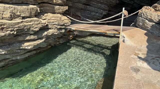 Natural Cavern Mouth with Transparent Underground Stream and Modern Metal Bridge