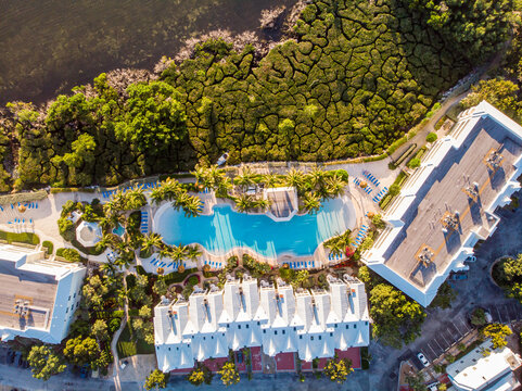 Key Largo, United States - 24 December 2019: Aerial view of a resort swimming pool surrounded by palm trees, white buildings, and lush mangrove vegetation along the coastline.