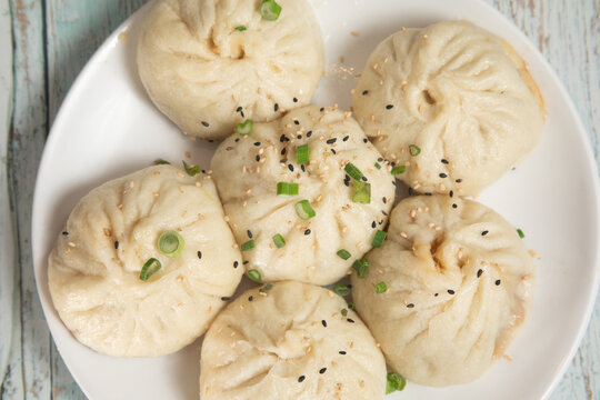 Ramen et bao sur une assiette en bois claire